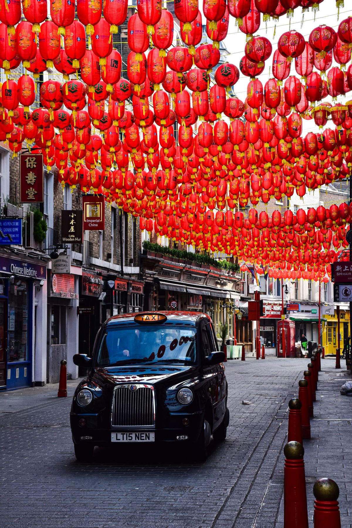 A classic London black cab beneath Chinatown lanterns